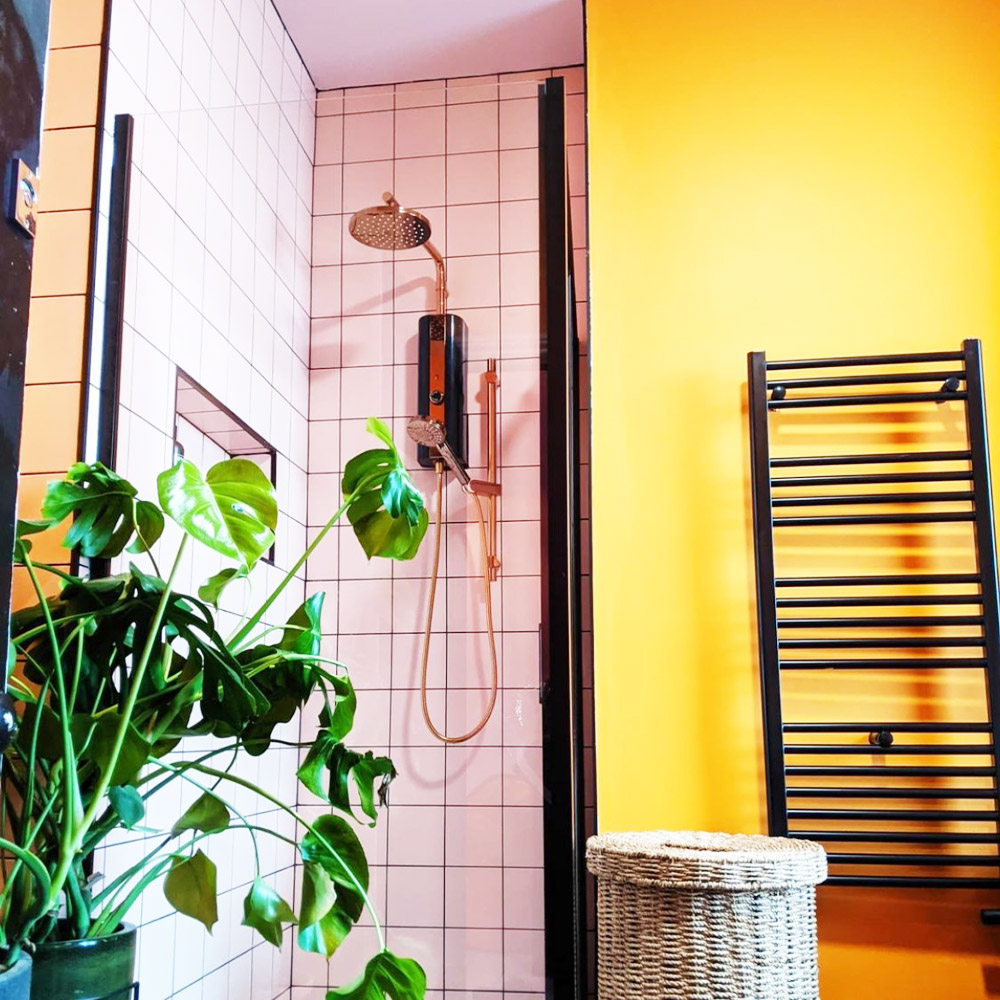 Bright and vibrant pink and yellow bathroom with black accents and metal hardware. 