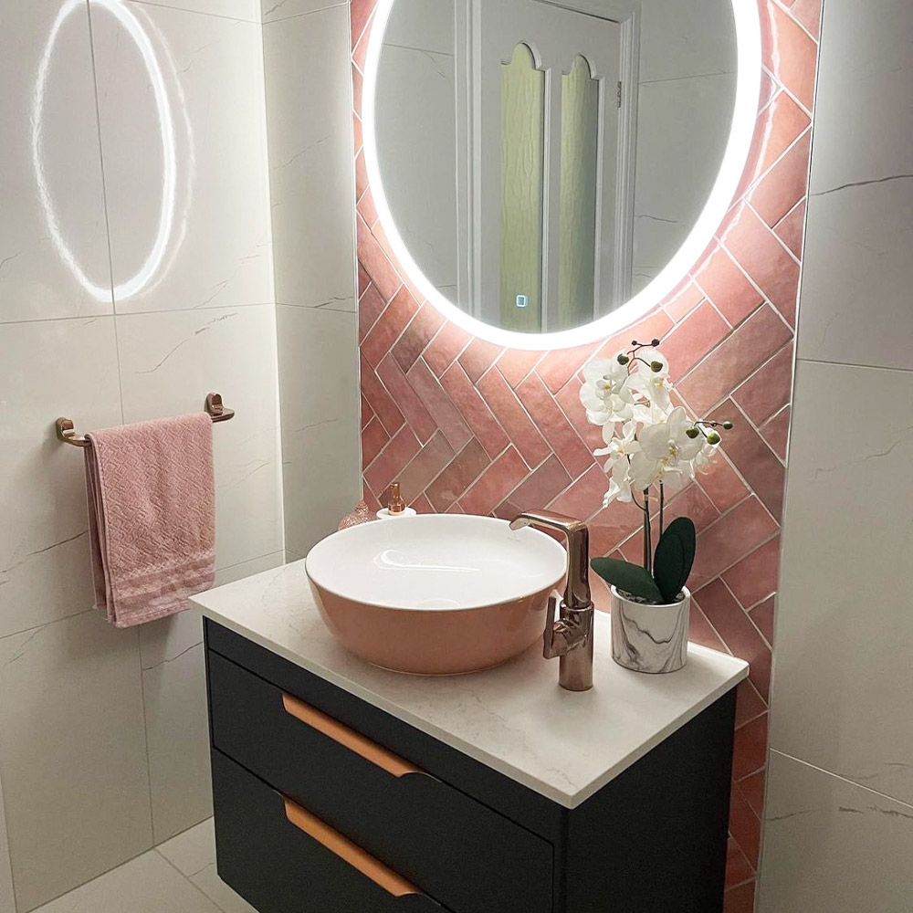 White and pink marble sink area with pink herringbone tiles as a boarder behind sink. 
