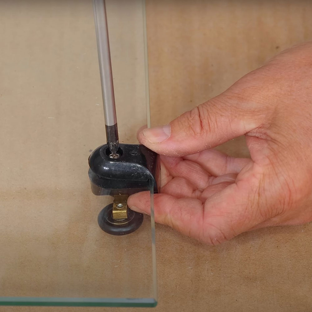Screwing rollers onto glass panel.