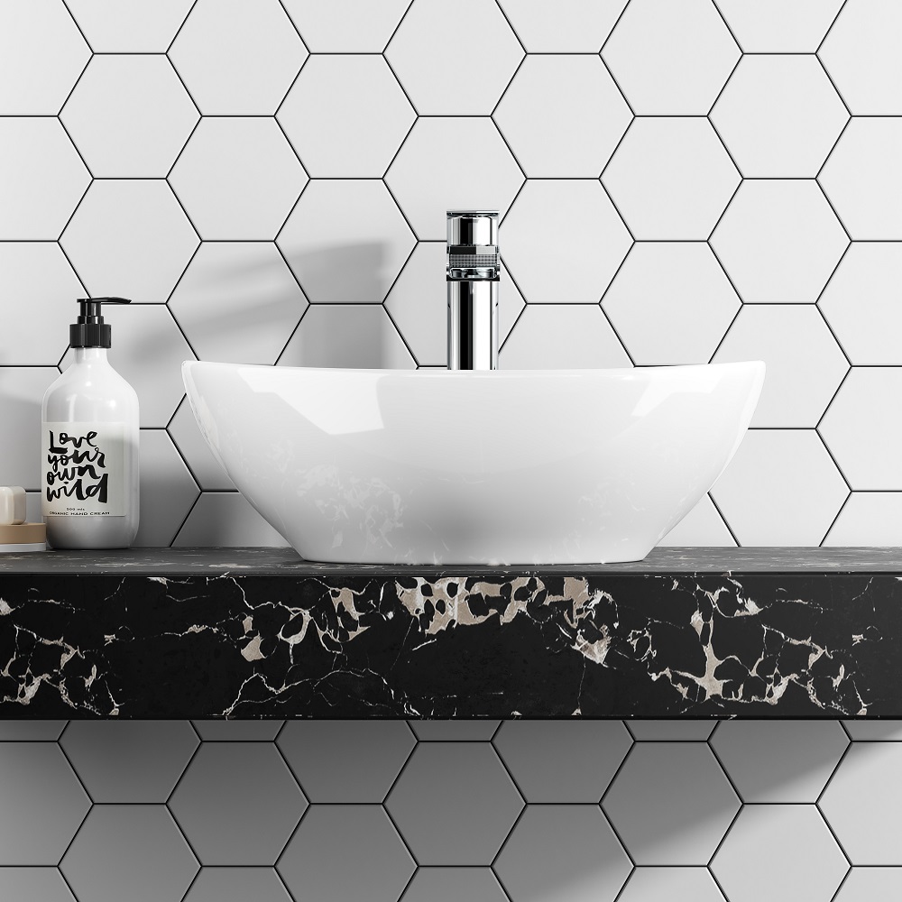 White hexagonal wall tiles across bathroom vanity with black marble counter top and oval white counter top basin. 