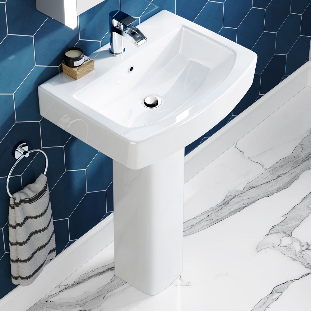 White square pedestal basin in blue bathroom with marble floor tiles and chrome tap and basin waste.