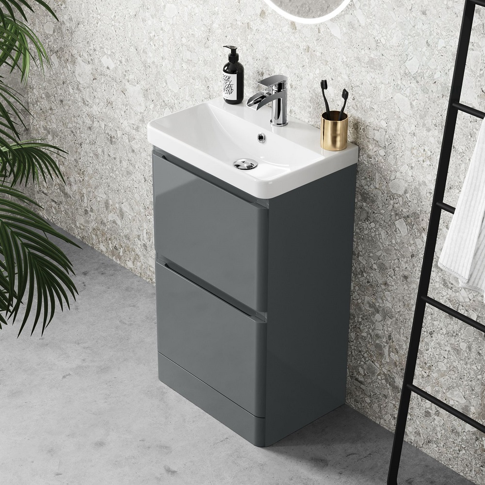 Grey modern floor standing vanity basin unit in stone effect bathroom with modern chrome waterfall tap.