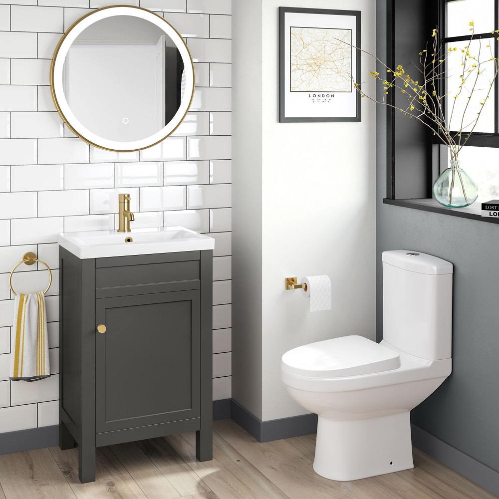 Grey bathroom scheme with white metro wall tiles and oak wood floor tiles, white toilet and modern basin vanity unit with gold metal hardware.