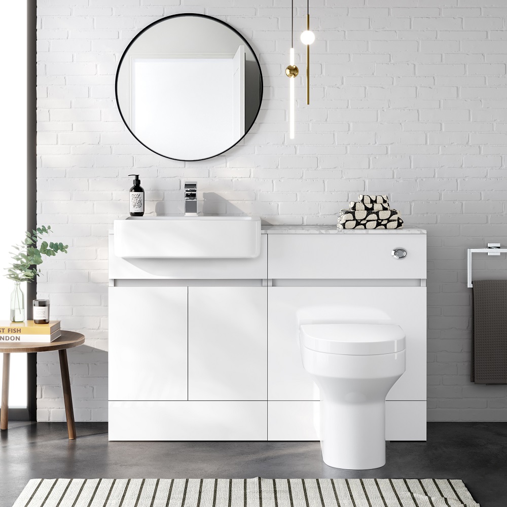 Contemporary bathroom with a white vanity and built-in sink, complemented by a round black-framed mirror on a white brick wall, chic decor touches, and a striped floor rug.