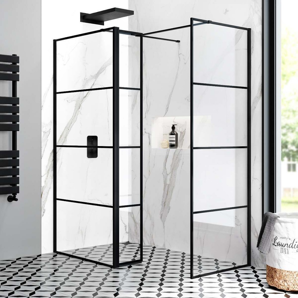 A corner shower cubicle with a sleek black frame, featuring clear glass panels with grid-like patterns, a rainfall shower head, and a built in niche for toiletries, set against marble-style wall tiles and a patterned monochrome floor. 