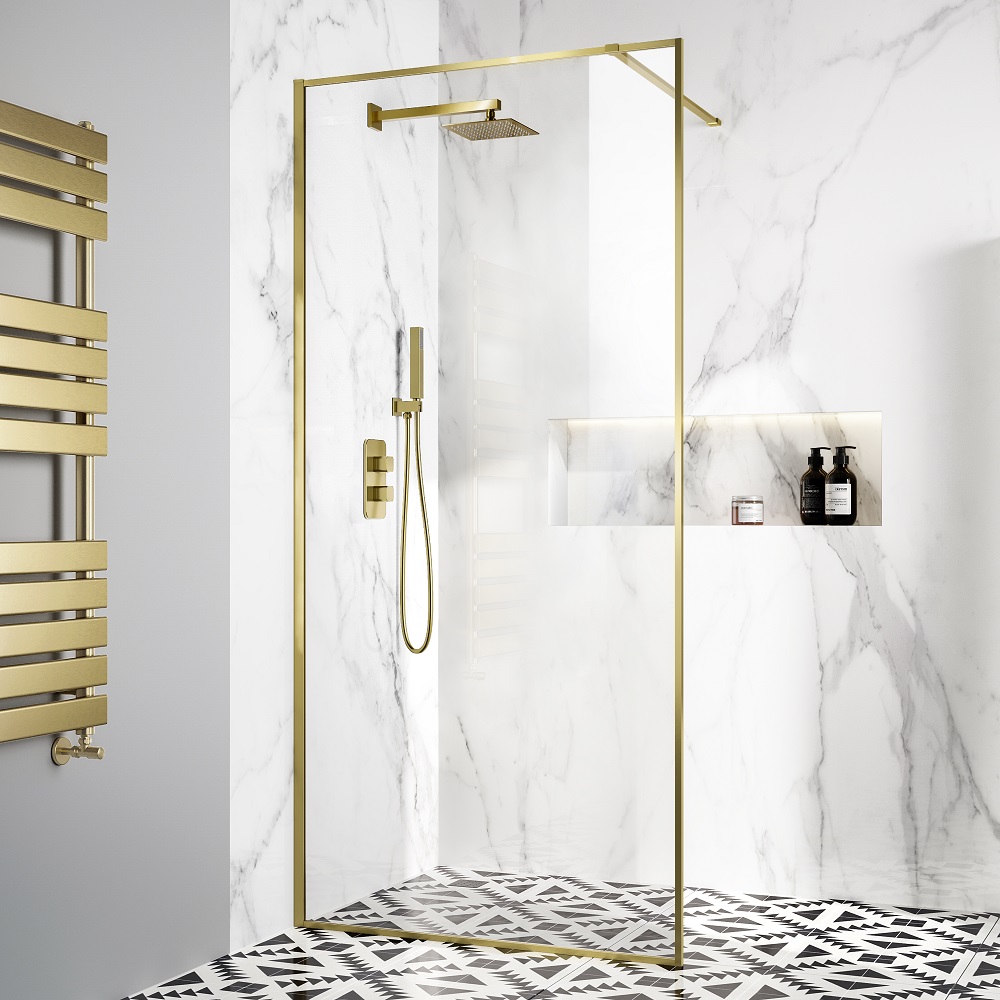 A luxurious shower enclosure with gold accents on the frame and fixtures, set against a backdrop of white marble wall tiles. A geometric-patterned floor tile adds a contrasting detail. A gold coloured heated towel rail on the left enhances the opulence of the design.
