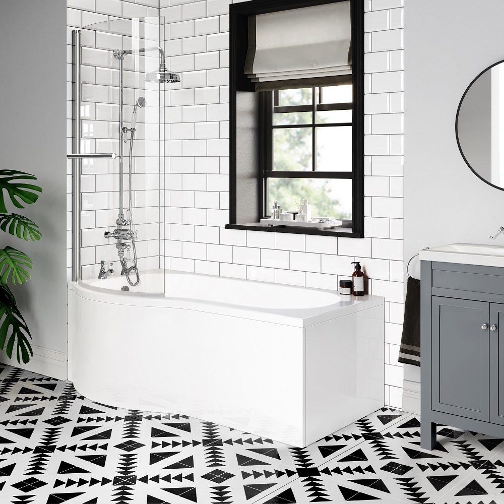A p-shaped shower bath with a glass screen and chrome fittings against a backdrop of white subway tiles. A black framed window complements the grey vanity unit and the bold, black and white geometric floor tiles. 