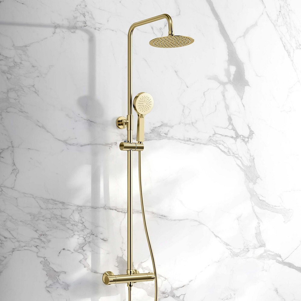 A brushed brass round thermostatic shower kit mounted on a marble wall, featuring a rain shower head and a handheld shower head, with a minimalist design that exudes luxury and elegance in a modern bathroom setting. 