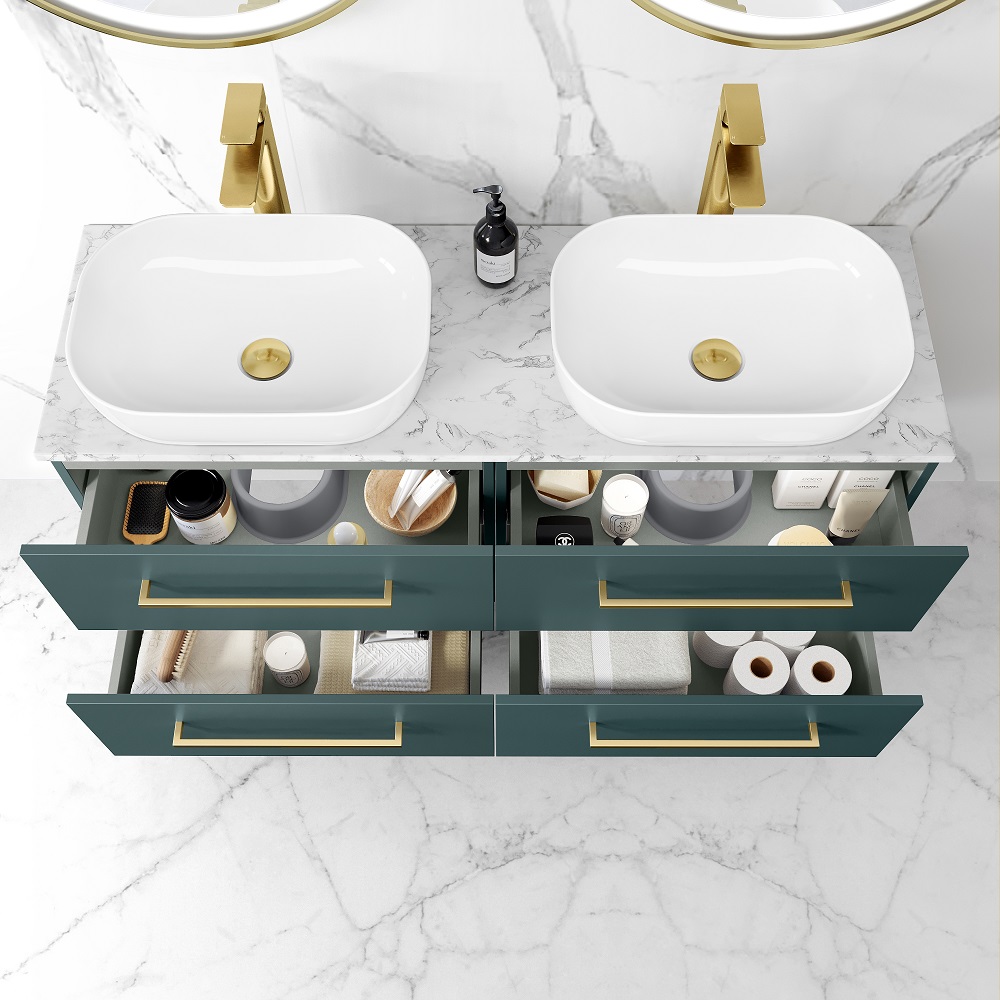 An overhead view of a midnight green double wall hung vanity with open drawers, revealing neatly organised bathroom essentials. The vanity has a marble top with two white curved basins, complemented by gold faucets. A black soap dispenser is placed beside the basins. The marble countertop rests against a marble wall with subtle veining, creating a luxurious and cohesive design. 