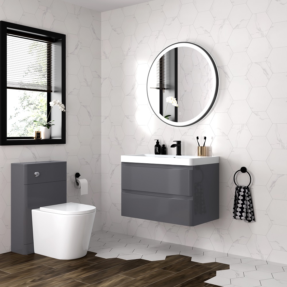 Modern bathroom with wall-hung grey vanity unit, basin and mirror, white geometric tiled walls, and herringbone brown floor tiles. Natural light floods in through window.