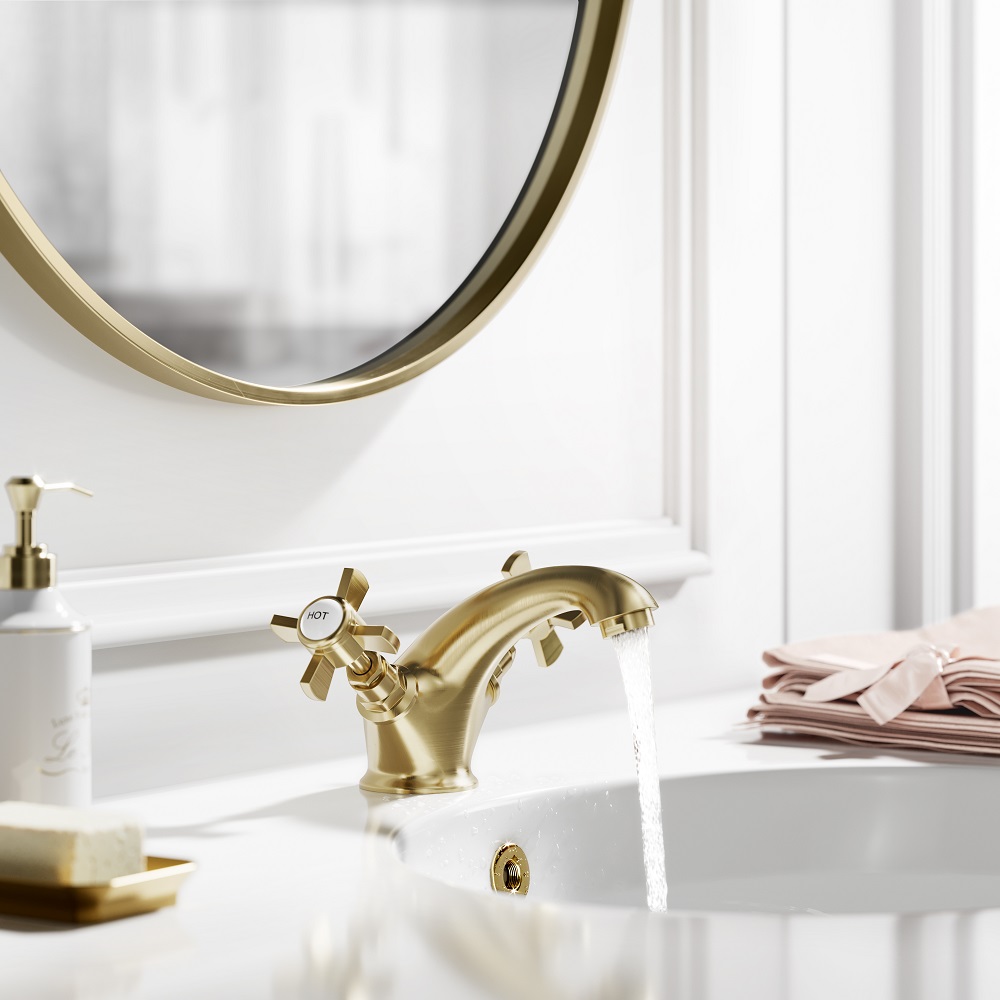 Luxurious brushed brass basin mixer tap with water flowing into a white sink, reflected in a circular mirror, creating a clean and elegant bathroom aesthetic. 