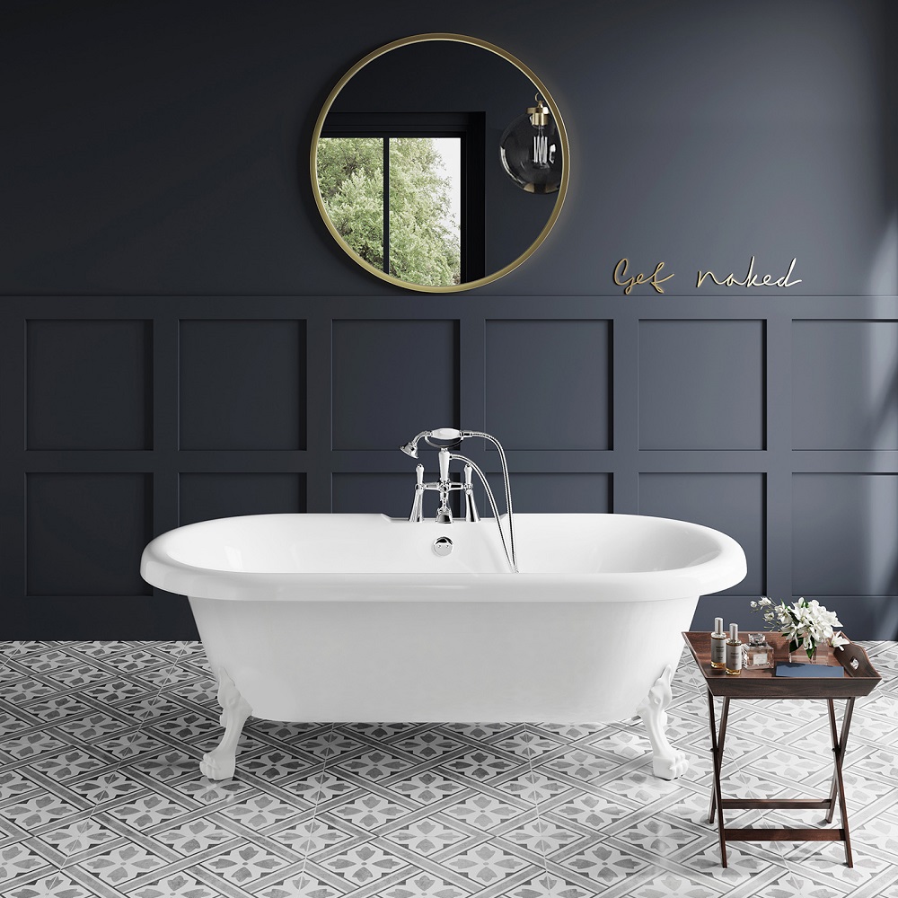 Classic white freestanding roll-top bathtub for roll top bath ideas in a chic dark grey panelled bathroom with decorative floor tiles, featuring a stylish round gold-framed mirror and a quirky 'get naked' wall art. 
