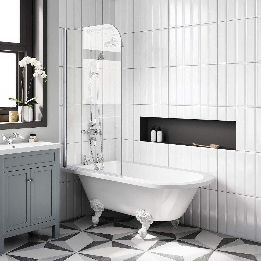 Chic monochrome bathroom featuring a sleek white roll-top shower bath with unique white ball feet, a clear glass shower screen, and subway tiled walls, accented by a charcoal niche and diamond-patterned floor tiles, embodying a modern twist on classic style. 